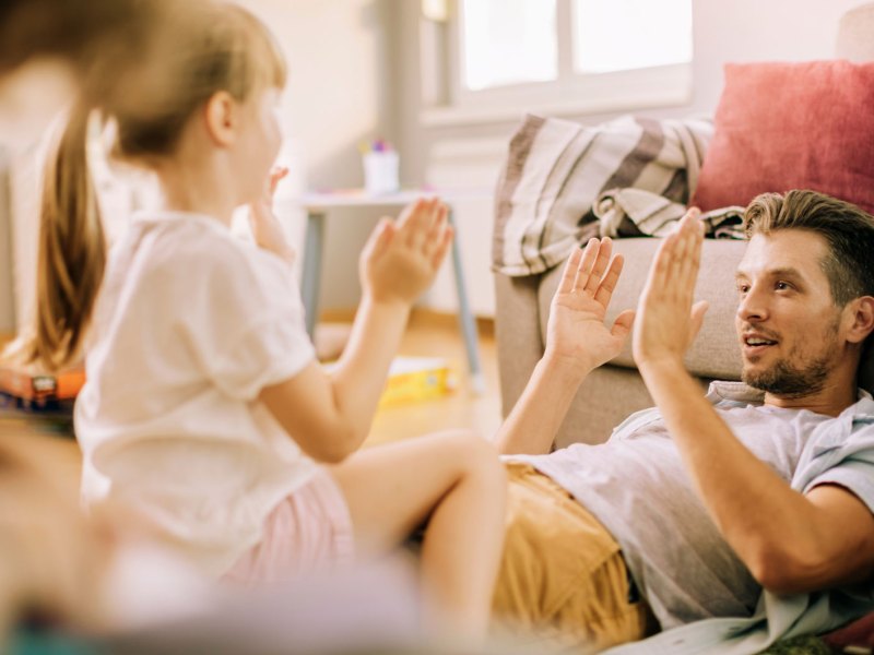 Vater und Tochter zu Hause spielen ein Abschlagspiel.