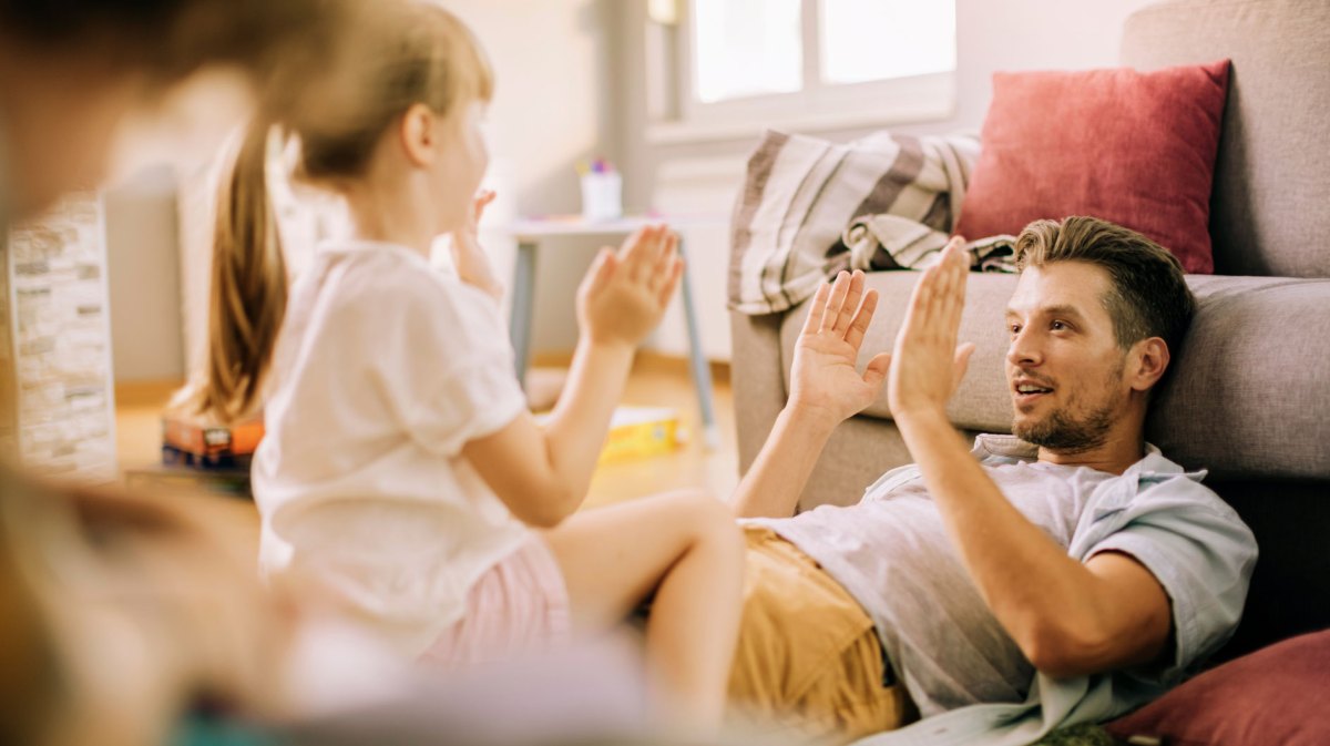 Vater und Tochter zu Hause spielen ein Abschlagspiel.