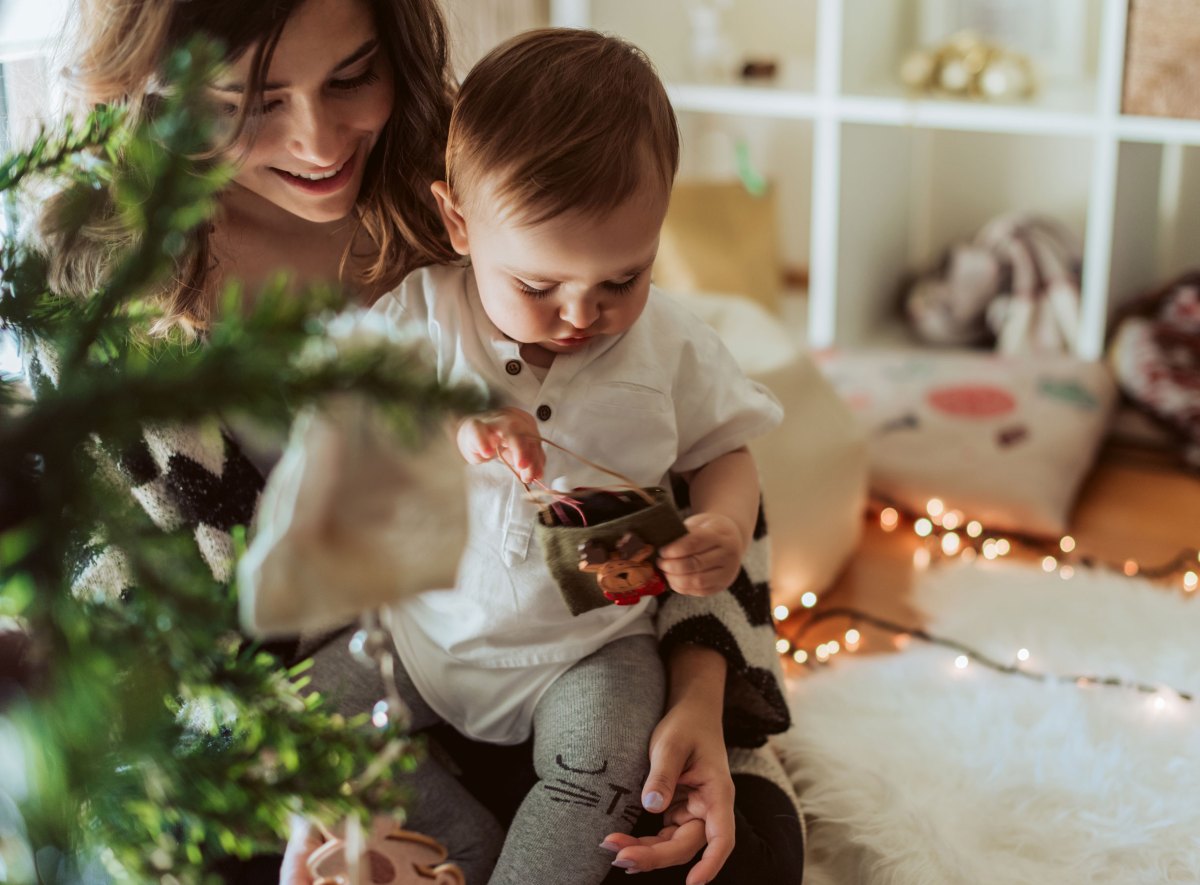 Mutter mit Baby unterm Weihnachtsbaum