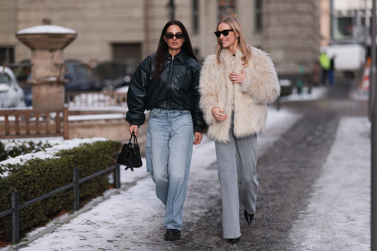 Zwei Influencerinnen, die weite Hosen tragen und durch den Schnee laufen.