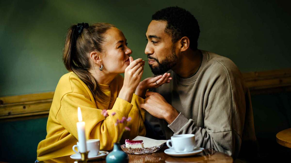 Verliebtes Paar füttert sich gegenseitig mit Kuchen.