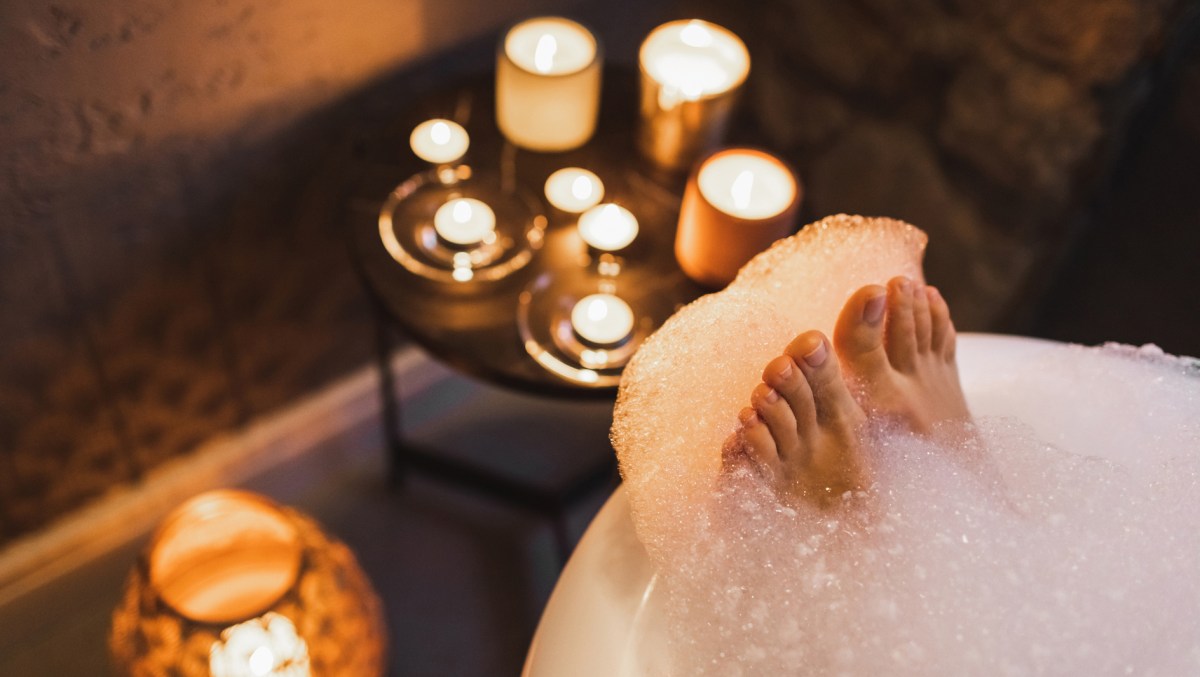 Frau entspannt sich in der Badewanne mit Kerzenlicht.