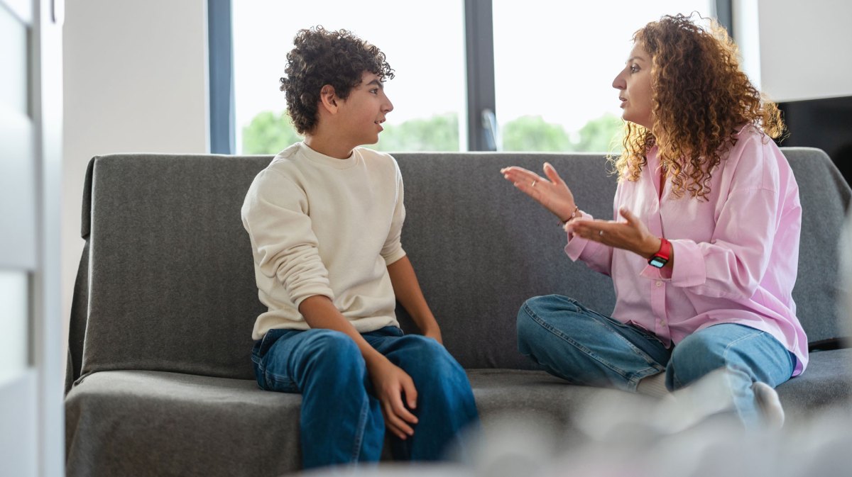 Sohn und Mutter sitzen auf dem Sofa und streiten sich.