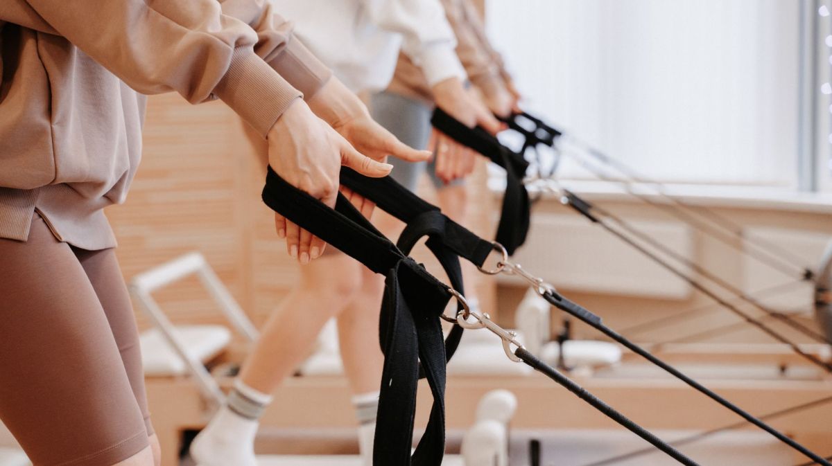 Frauen in Sportbekleidung auf einem Pilates-Reformer