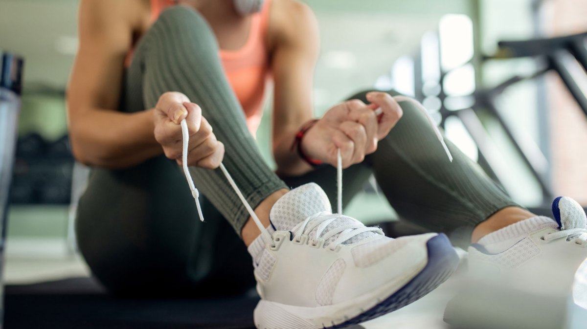 Frau in Sportbekleidung bindet sich ihre Sportschuhe.