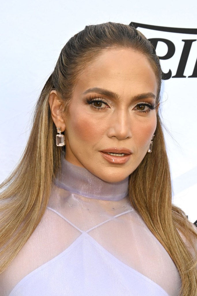 Jennifer Lopez mit zurück gekämmten Haaren und Half Bun.