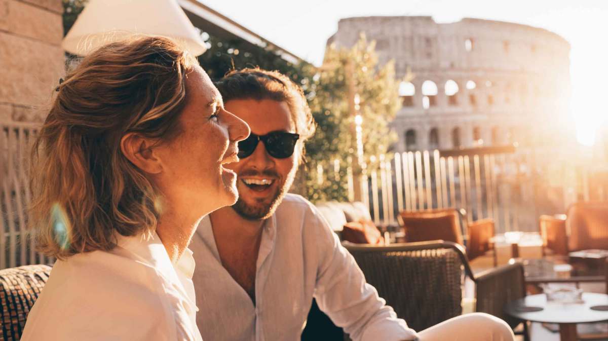 Frau und Mann sitzen draußen und lachen in der Sonne.