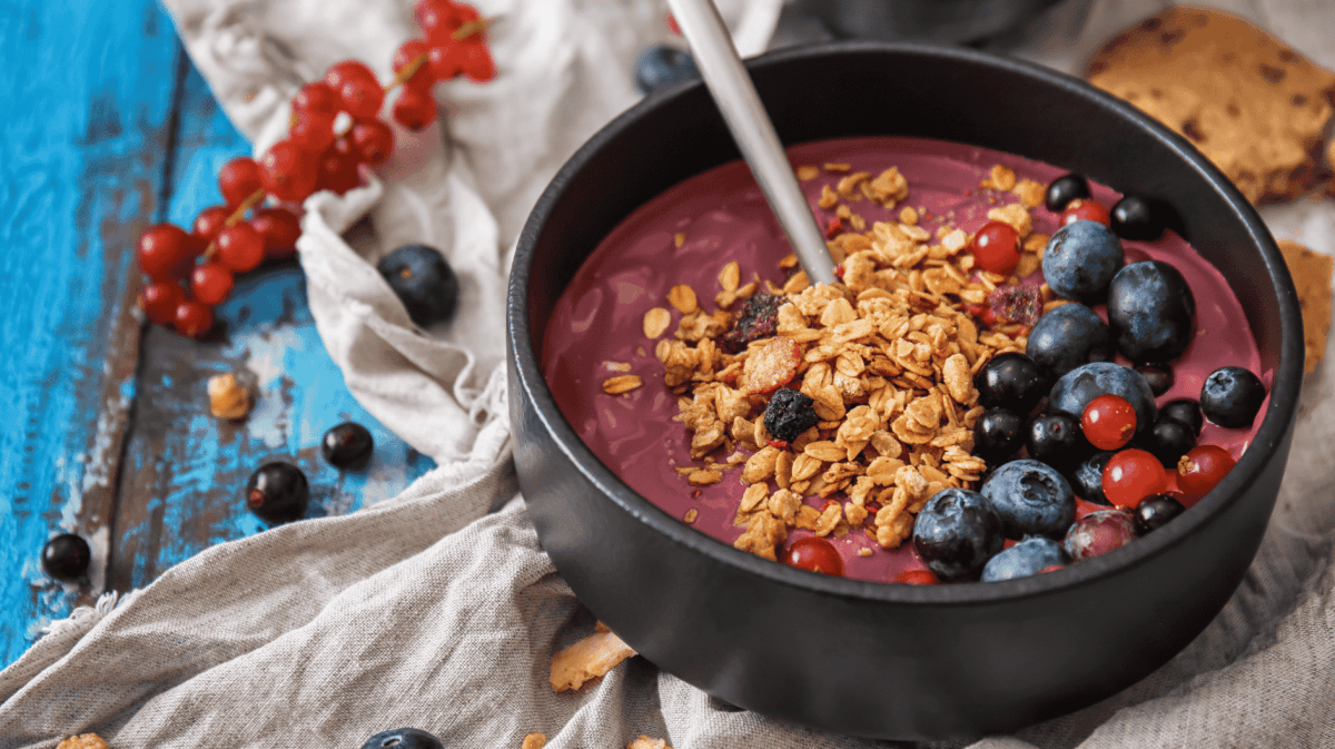 Smoothie Bowl in einer Schale mit Blaubeeren, Johannisbeeren & Granola als Topping