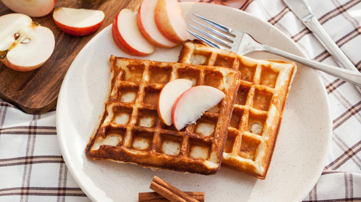 Waffeln auf einem weißen Teller mit Apfelscheiben darauf.