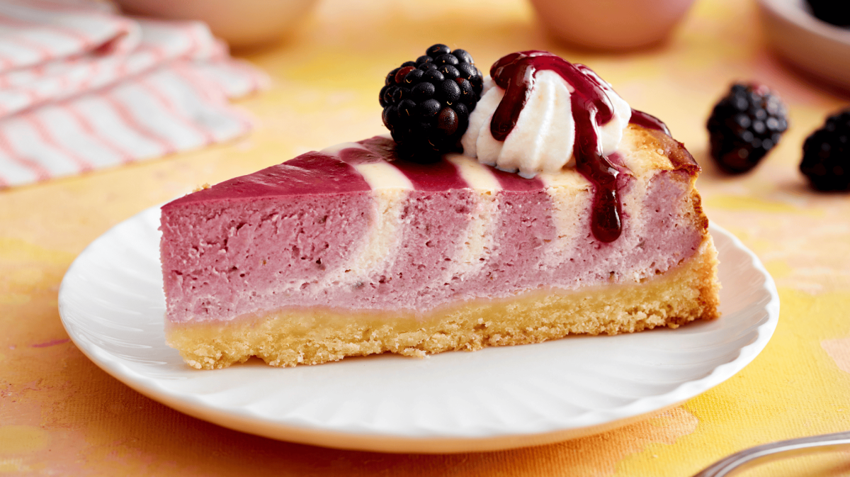 Ein Stück Käsekuchen mit Zebramuster und Brombeeren.