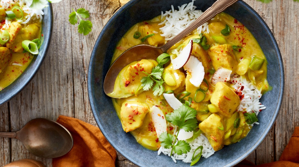 Curry-Putengulasch auf Reis in einer hellblauen Schale.