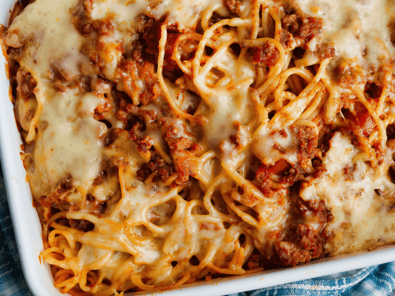 Spaghetti Nudelaufalfu mti Bolognese und Käse in weißer Auflaufform.