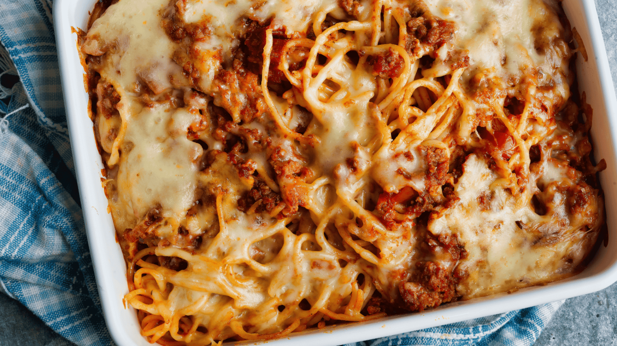 Spaghetti Nudelaufalfu mti Bolognese und Käse in weißer Auflaufform.