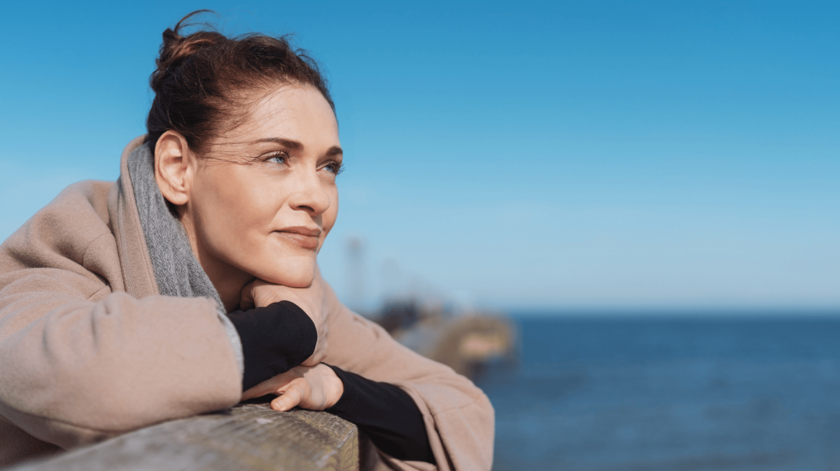 Junge Frau schaut aufs Meer hinaus.