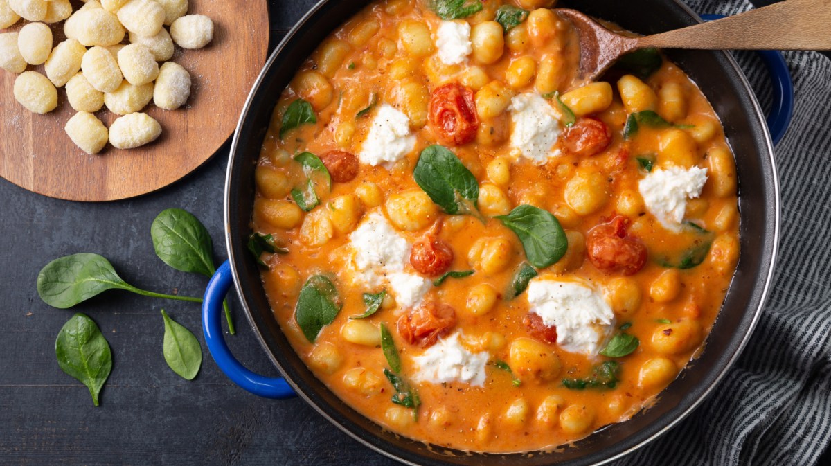 Gnocchi mit Baslikum, Tomatensoße und Käse in einem großen Topf.