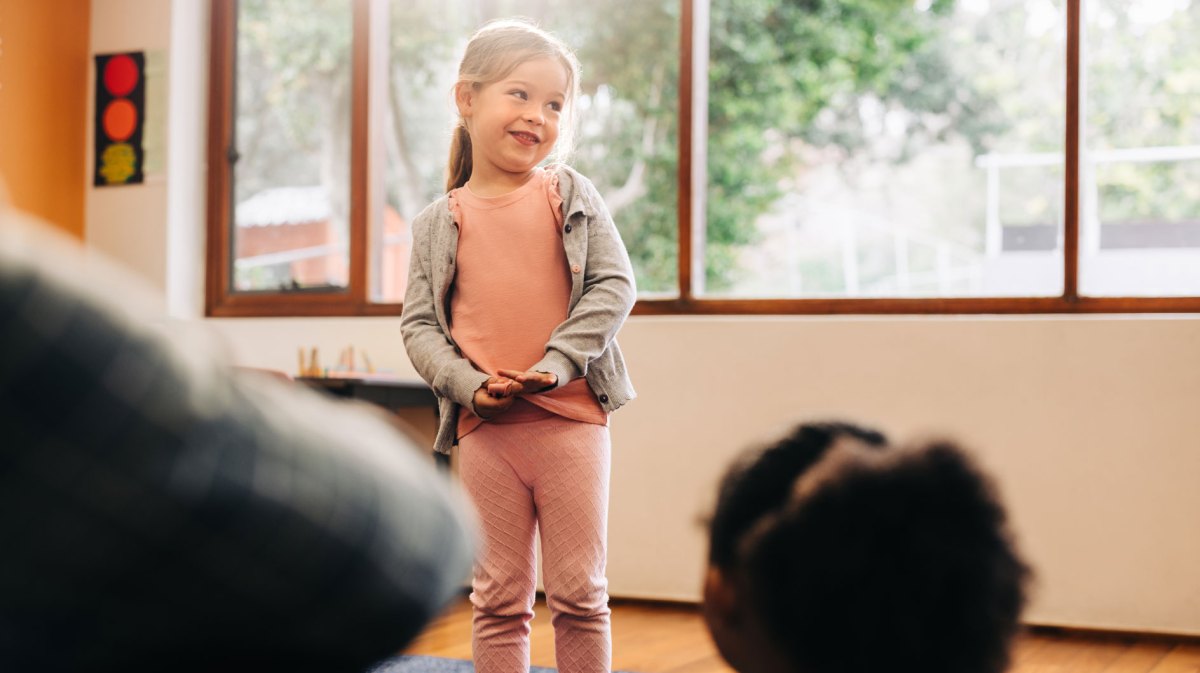 Schüchternes Mädchen steht vor ihrer Klasse und hält einen Vortrag.