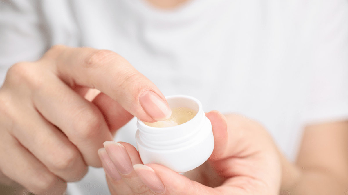 Eine Frauenhand nimmt etwas Vaseline mit dem Finger aus der Dose