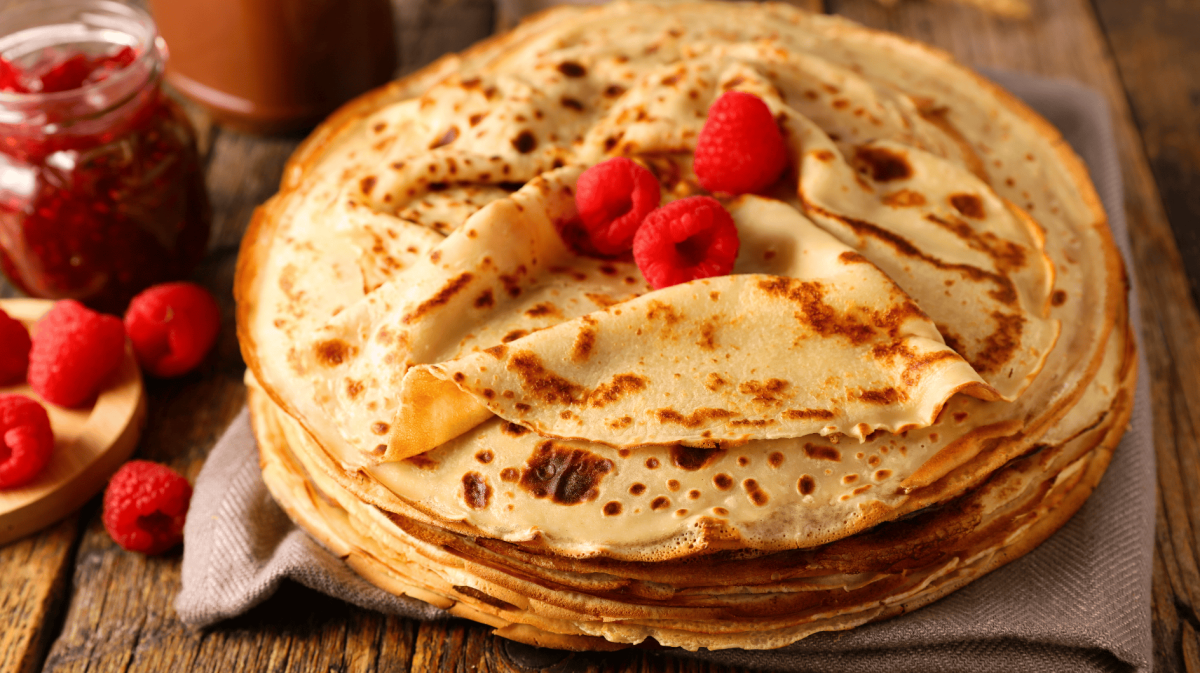 Ein großer Stapel dünner Pfannkuchen auf einem Holztisch.