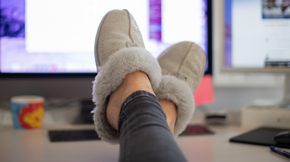 Füße mit Hausschuhen auf dem Schreibtisch im Homeoffice