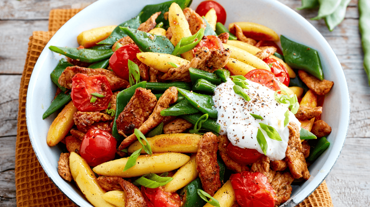 Gyros-Schupfnudel-Pfanne mit Tomaten und grünen Bohnen auf einem weißen Teller.